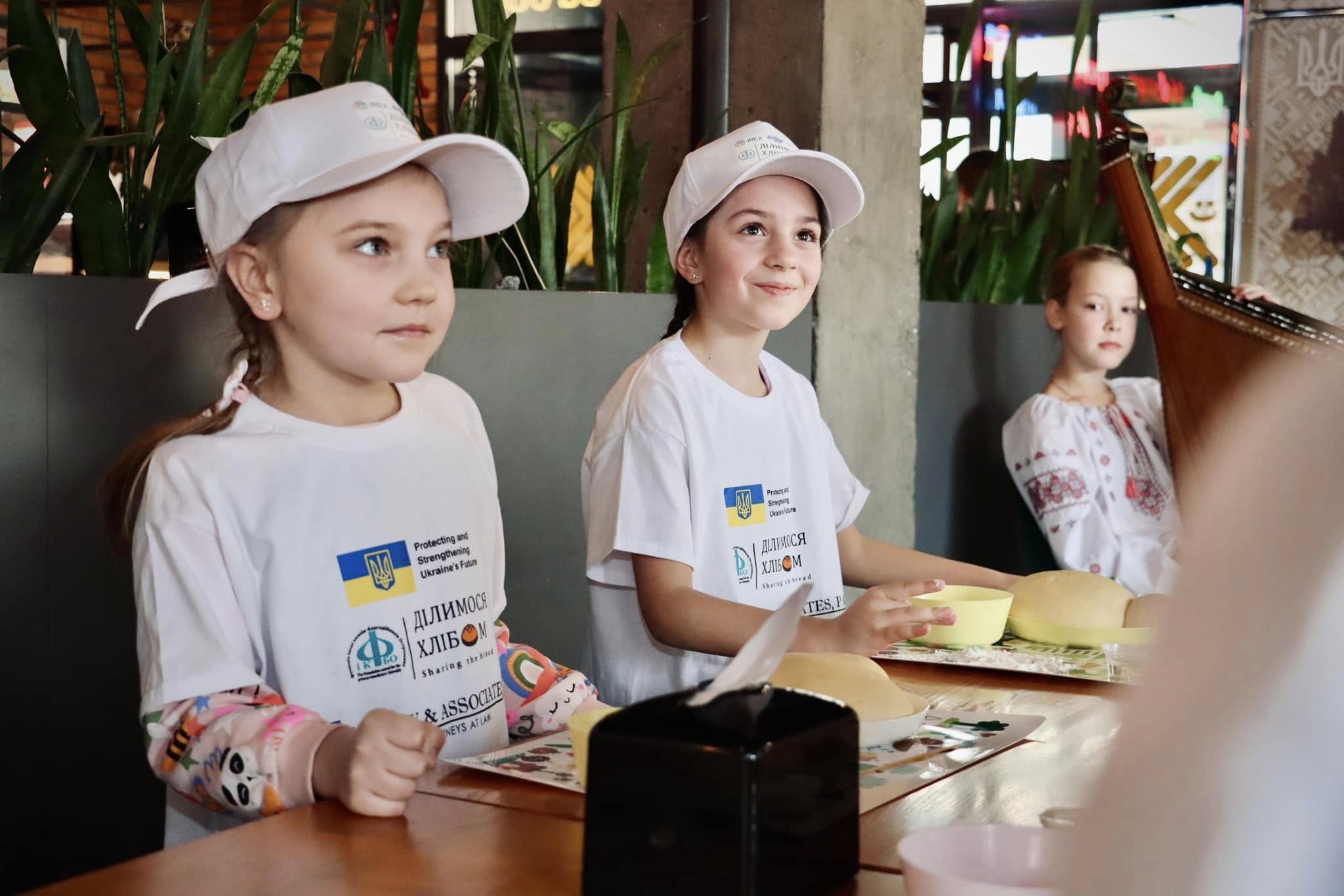 Діти у білих футболках посміхаються.